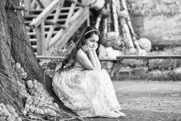 Ağaç ve sarı güller yakınındaki küçük kız