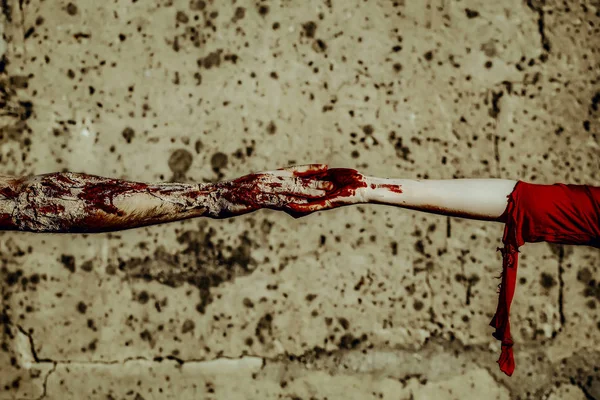 Хеллоуїн два зомбі торкаються пальців на бетонній стіні — стокове фото