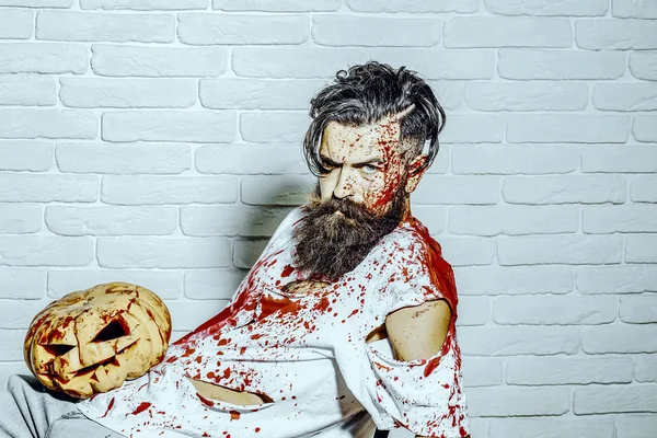 Cadılar Bayramı Balkabağı beyaz tuğla duvar ile oturan adam