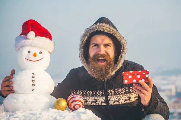 Ευτυχισμένος hipster και χιονάνθρωπο σε santa καπέλο στον γκρίζο ουρανό — Φωτογραφία Αρχείου
