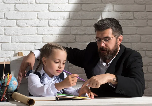 Colegiala y papá con caras ocupadas aprenden a escribir —  Fotos de Stock