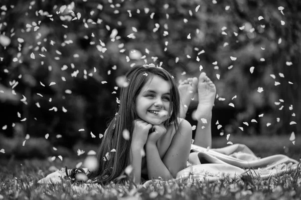 Yaprakları yeşil çimenlerin üzerinde küçük kız