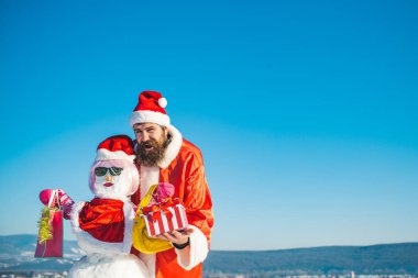 Kardan adam pembe peruk, eldiven ve gözlük ile alışveriş torbaları