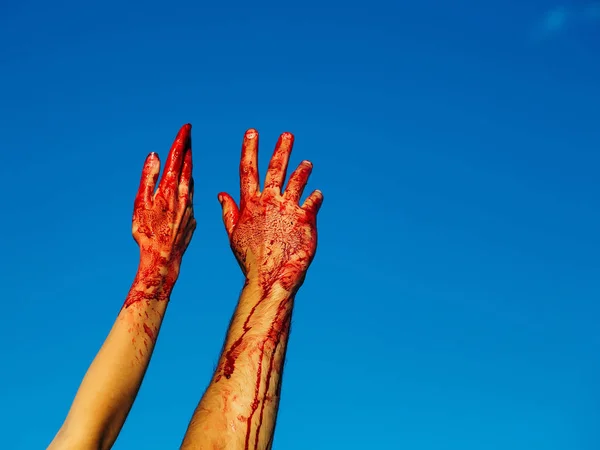 Blodiga zombie händer med rött blod på blå himmel — Stockfoto
