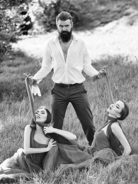 Sakallı adam ve iki kadınla çimenlerin üzerinde