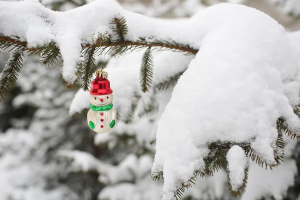 Hóember játék lóg a fenyő-ban téli fa háttér — Stock Fotó