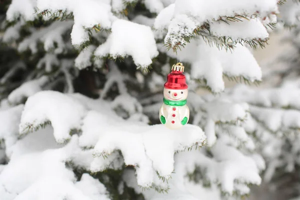 Snowman toy hanging on branch covered with snow — Stock Photo, Image