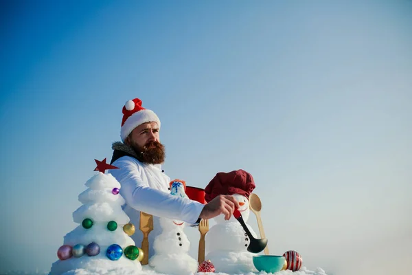 Man in rode kerstmuts koken op winterdag — Stockfoto