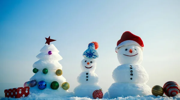 Snow sculptures with smiley faces in hats on winter day — Stock Photo, Image