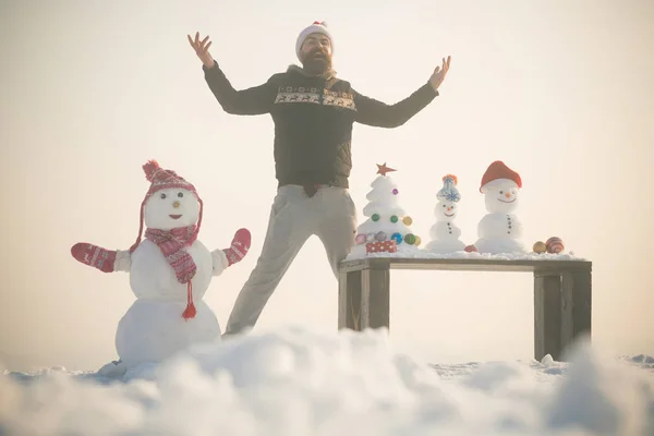 Hipster und Schneemann mit erhobenen Händen am weißen Himmel — Stockfoto