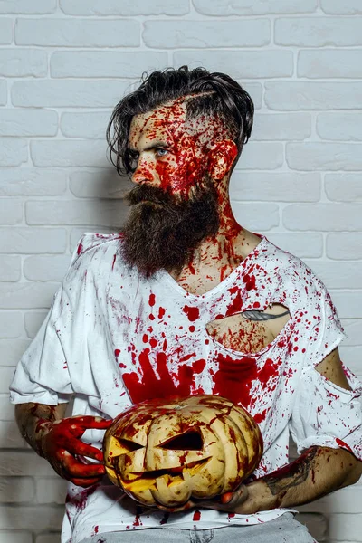 Halloween man holding pumpkin on white brick wall — Stock Photo, Image