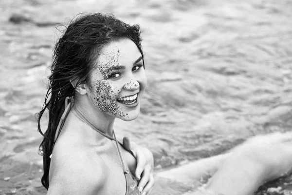 Όμορφος ευτυχισμένος κορίτσι με άμμο στο χαμογελαστό πρόσωπο στη θάλασσα — Φωτογραφία Αρχείου