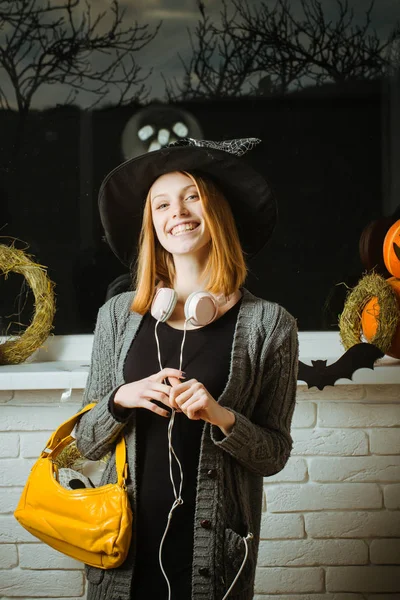 Halloween fille en chapeau de sorcière avec écouteurs et sac souriant — Photo