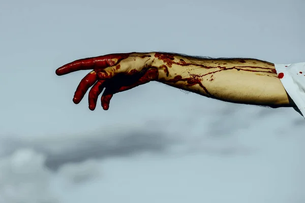 Кровавая рука Хэллоуина на фоне серого неба — стоковое фото