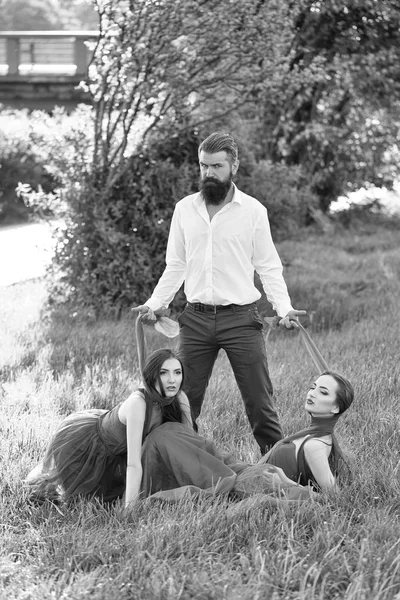 ひげを生やした男性と芝生の上の 2 人の女性 — ストック写真