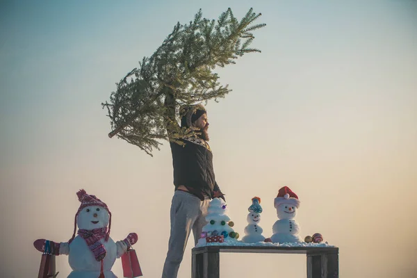 Man verhogen kerstboom op blauwe hemel — Stockfoto