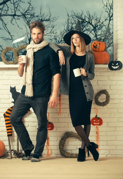 Halloween férfi és nő a gazdaság csésze boszorkány kalap — Stock Fotó