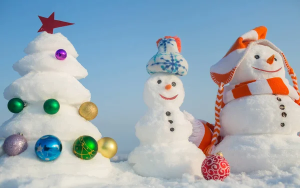 Esculturas de neve com rostos sorridentes em chapéus no dia de inverno — Fotografia de Stock