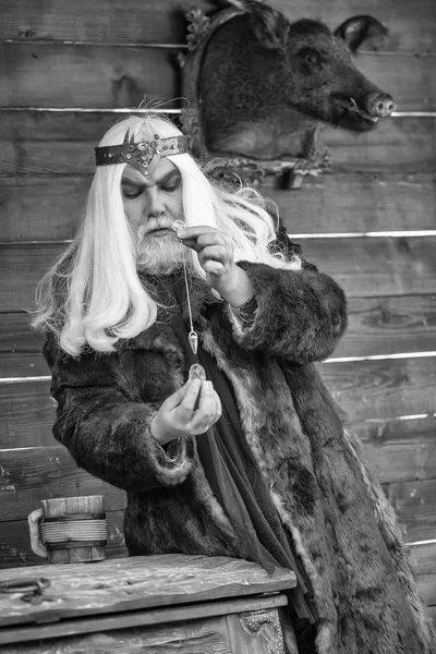 Old wizard with stone and pendant for hypnosis