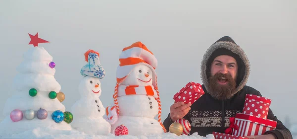 Hipster glimlachend met sneeuwmannen en besneeuwde kerstboom — Stockfoto