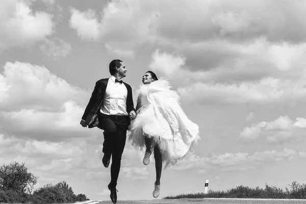 Casamento casal feliz correndo na estrada — Fotografia de Stock