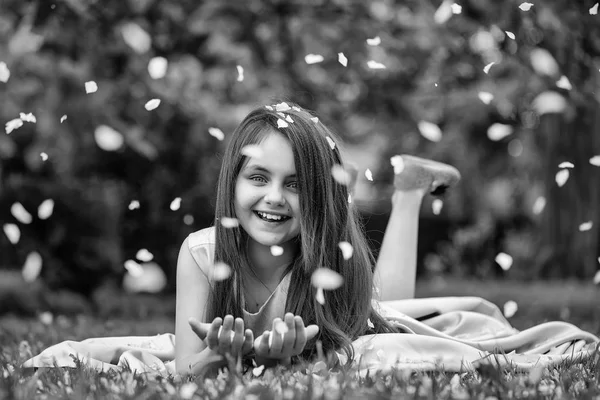 Yaprakları yeşil çimenlerin üzerinde küçük kız