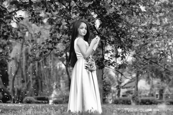 Girl in dress with notebook and pen in garden — Stock Photo, Image