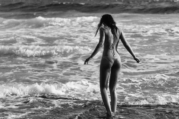 Bella ragazza in costume da bagno giallo sexy che cammina nel mare ondulato — Foto Stock