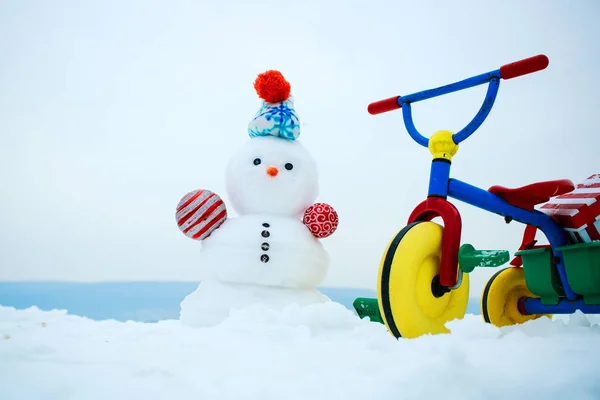 Üç tekerlekli bisiklet ve karlı arka plan kardan adam — Stok fotoğraf