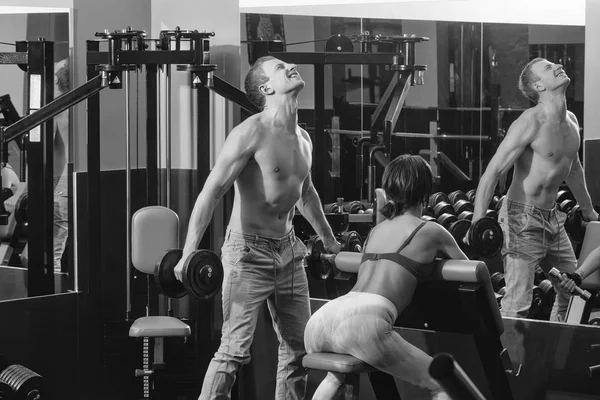 Muscoloso uomo e ragazza in palestra con manubri e bilanciere — Foto Stock