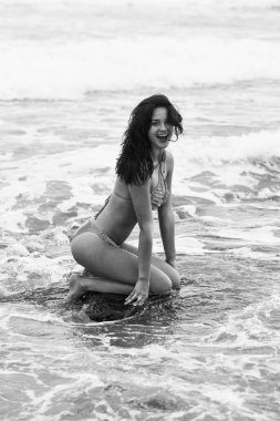 Kayanın üzerinde oturan sexi sarı mayo oldukça mutlu kız