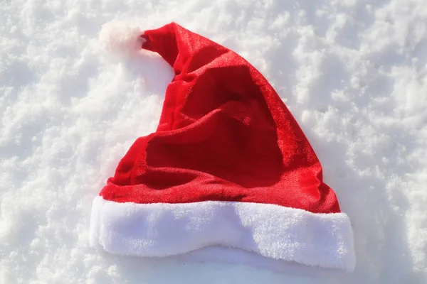 Красная шапка Санты на снегу — стоковое фото