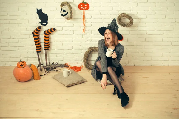 Halloween kvinna i häxa hatt blinkar med cups — Stockfoto