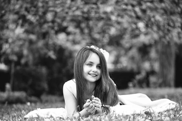 Yaprakları yeşil çimenlerin üzerinde küçük kız