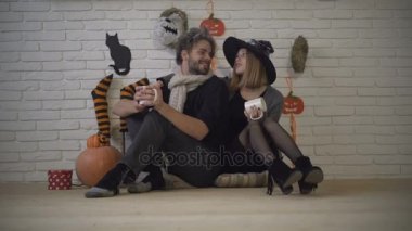 Halloween çift, parti eve ilk Kasım, Cadılar Bayramı sahne dekorasyonu, sıcak çay ve kabak. Mutlu çift, adam ve kız birlikte gülmek, katta oturmak ve tüm azizler günü kutlamak. Rahat ev