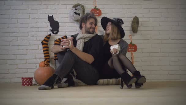 Halloween pár fél hazai első november, halloween dekoráció táj, meleg tea és tök. Boldog pár, fiú és lány együtt nevetni, a padlón ül, és ünnepeljük minden szentek napján. Hangulatos ház — Stock videók