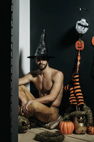 Halloween macho con cappello da strega e busto scoperto seduto — Foto Stock