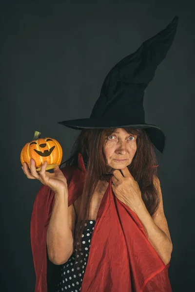 Halloween señora mayor sosteniendo la calabaza sobre fondo negro — Foto de Stock