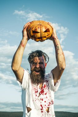 Kabak ek yükü bulutlu mavi gökyüzü üzerinde tutarak Cadılar Bayramı adam