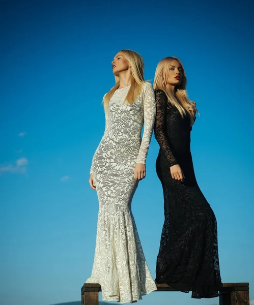 Uzun sarı saçlı mavi gökyüzü üzerinde poz iki kız