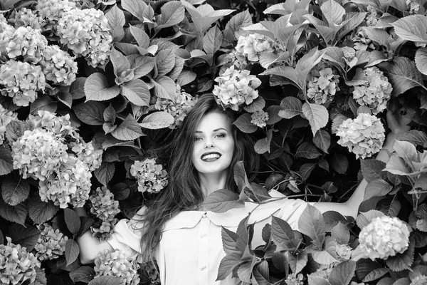 Bella ragazza sorridente in fiori ortensia — Foto Stock