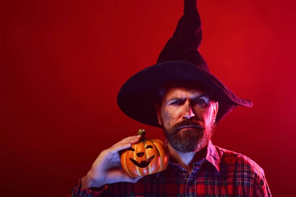 Halloween hipster in wizard hat holding pumpkin