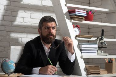 Profesör konsantre yüz ifadesi ile masa başında oturur