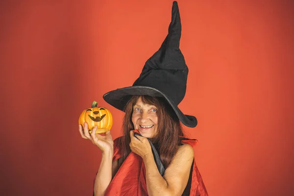 Mujer de Halloween sonriendo con calabaza sobre fondo rojo — Foto de Stock