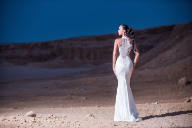 Kum tepeleri üzerinde dağ manzarası içinde gelin