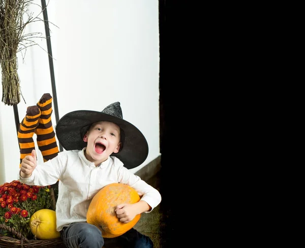 Halloween niño con calabaza naranja en sombrero de bruja —  Fotos de Stock