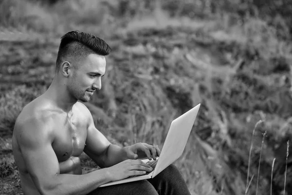 Συλλογισμένος μυώδης άνδρας με laptop που εξωτερικά — Φωτογραφία Αρχείου