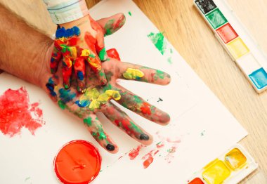 Renkli boyalar ve beyaz kağıt üzerinde çok renkli palet elinde