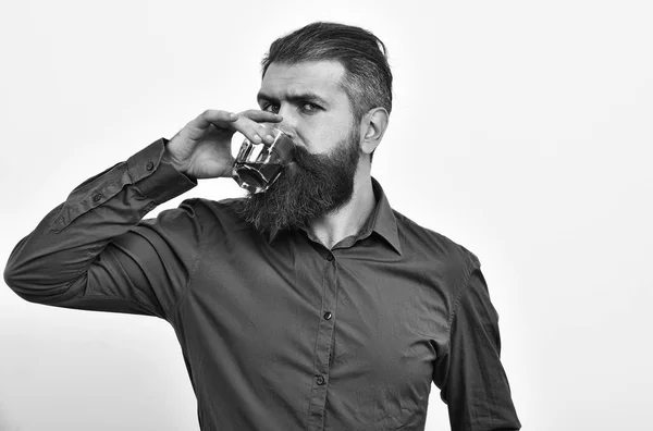 Hombre barbudo serio hipster con vaso de whisky en camisa naranja — Foto de Stock