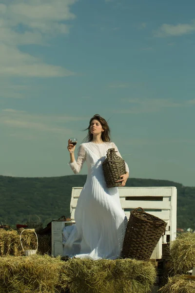 Donna con bicchiere di vino, bottiglia di vimini e cesto — Foto Stock